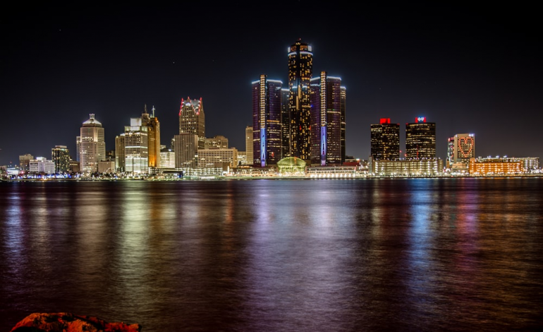A nighttime view of the Detroit, Michigan skyline with the Detroit River in the foreground