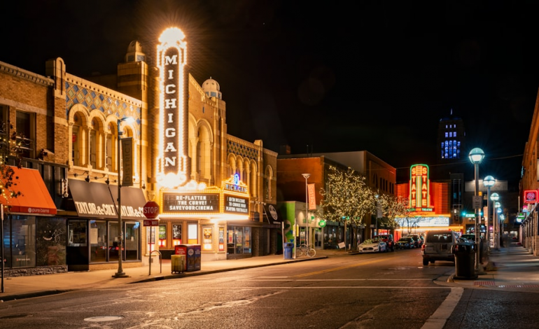 Downtown street at night featuring the lit-up Michigan Theater marquee and nearby businesses.