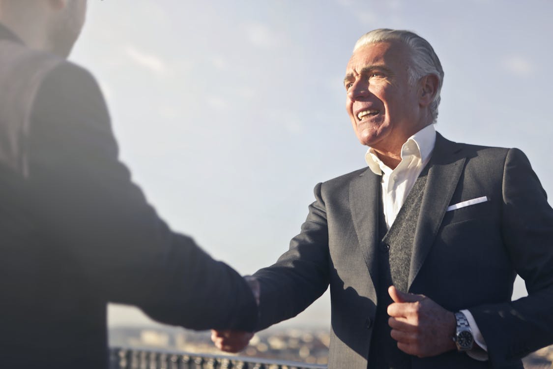 A real estate investor confidently shaking hands with a loan expert after finalizing financing.