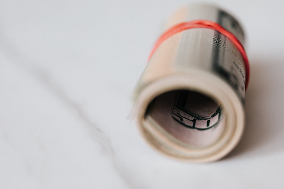 An image of US dollar banknotes rolled and tightened with red band