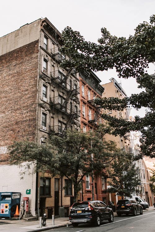 An image of a multifamily building with cars parked on the road