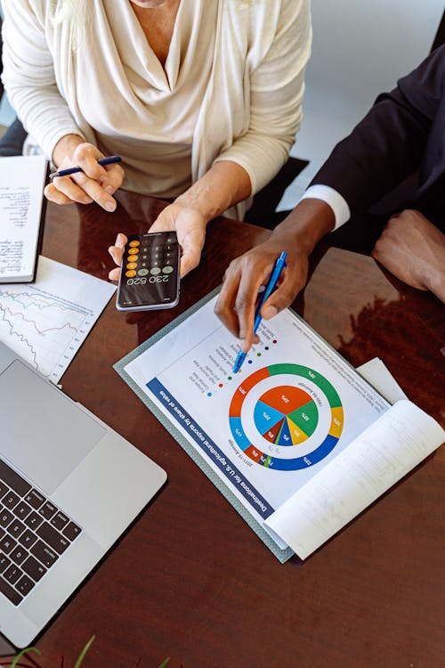 An image of two people working a marketing material using a pen and calculator on a phone