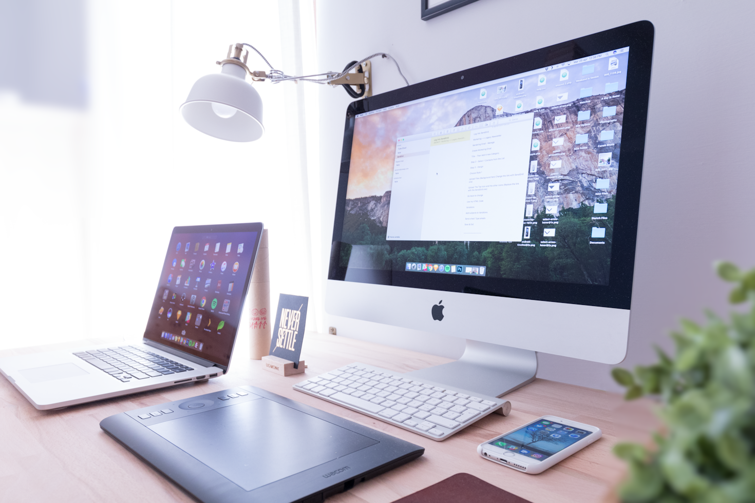 A computer, laptop, and other gadgets on a table 