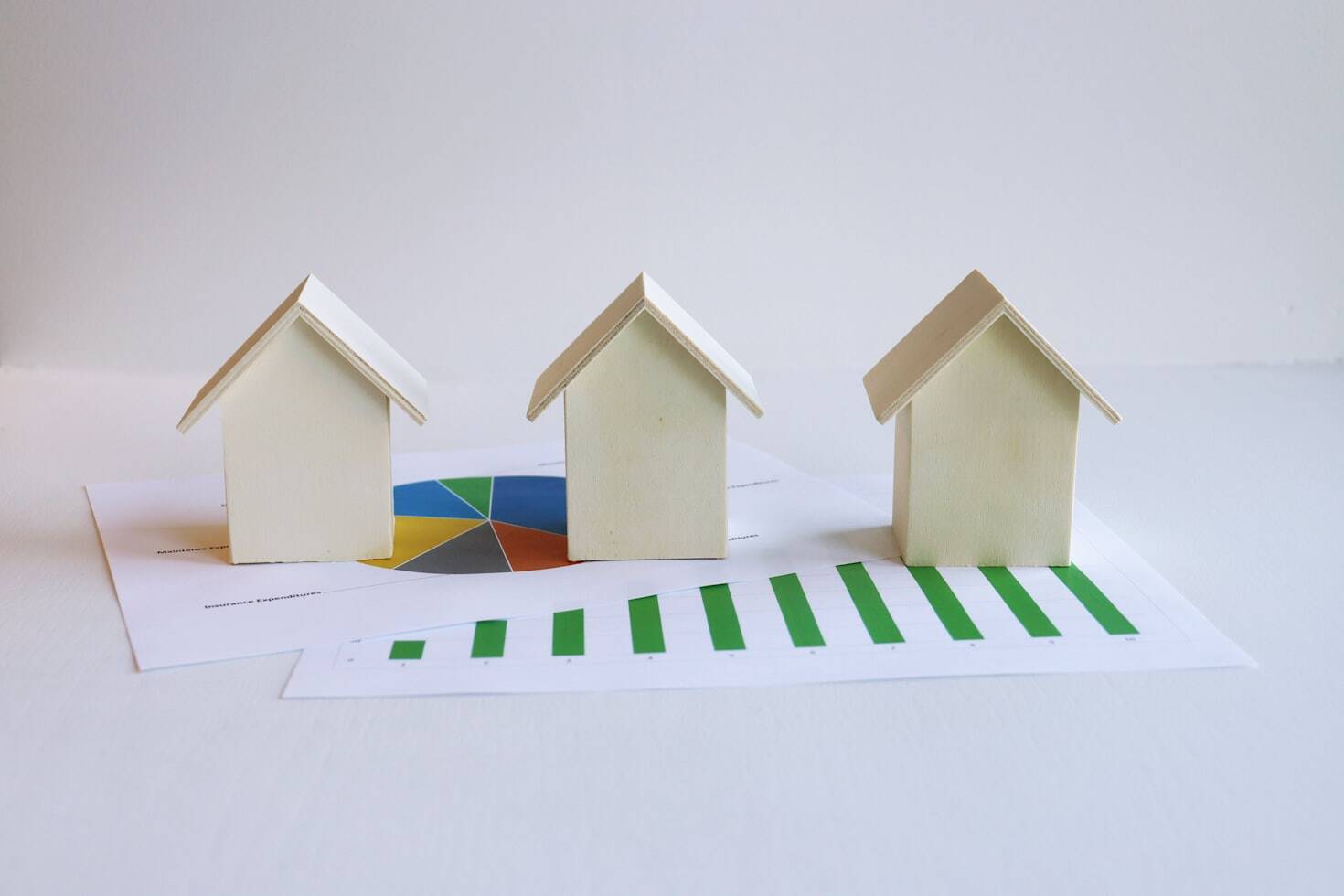 3 miniature houses on a real estate market trends charts