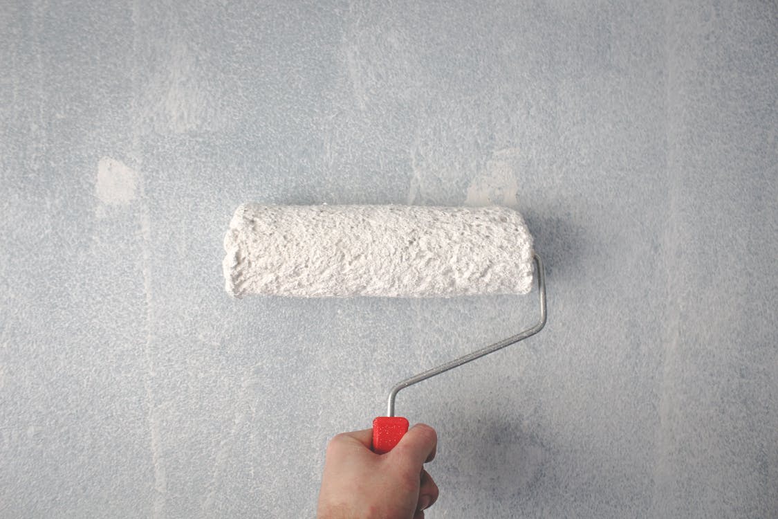 A person painting a wall with a paint roller