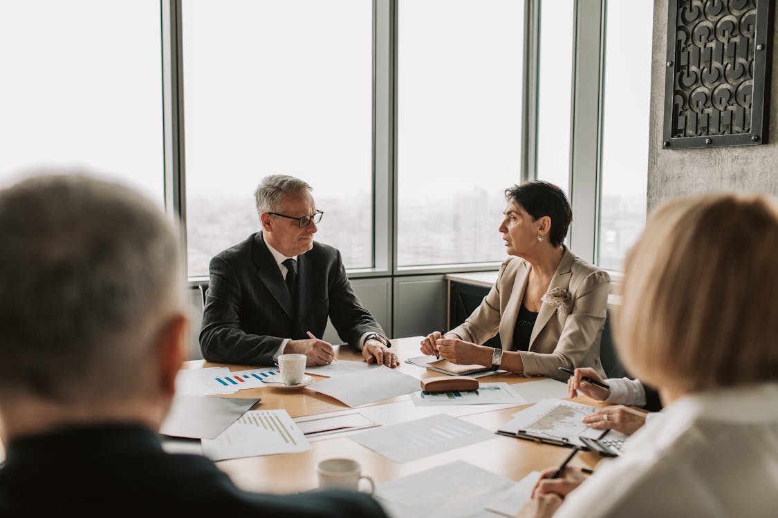 A meeting between real estate professionals discussing strategies to balance investment risks with potential rewards in a high-rise office.