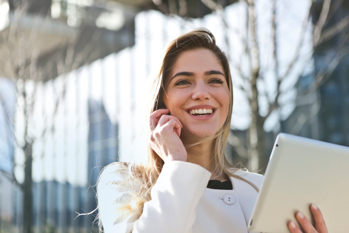 A Smiling Real Estate Investor Holding up a Tablet While Speaking on the Phone