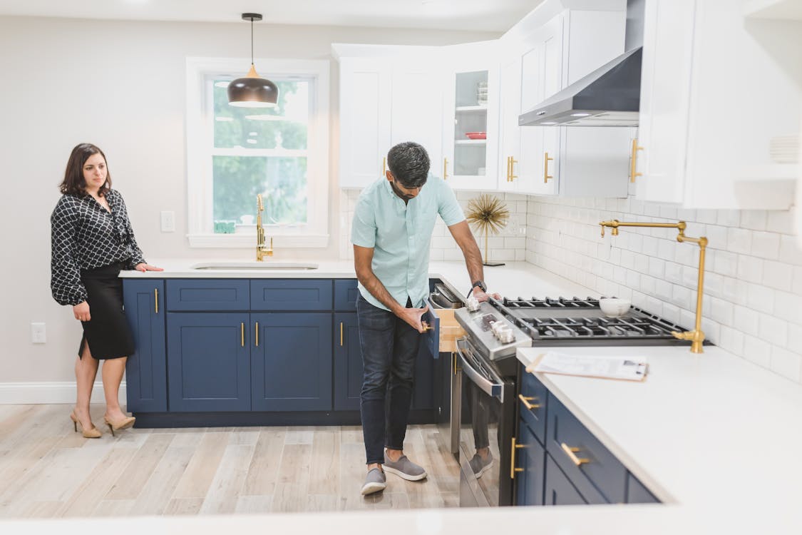 A real estate lender evaluating a kitchen of a house while the female real estate agent stands at the back