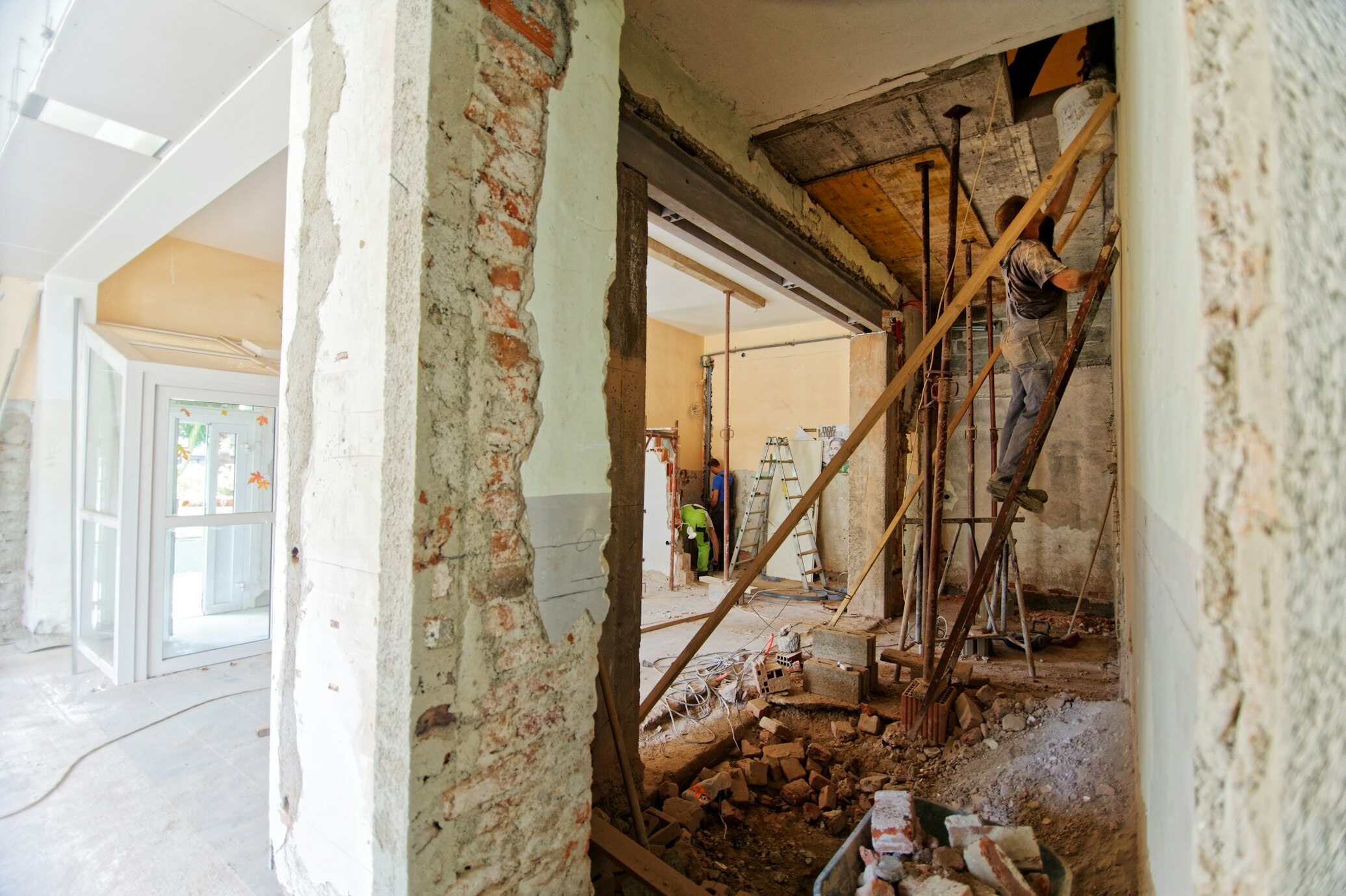 A man on a ladder working on a ceiling while renovating a house 