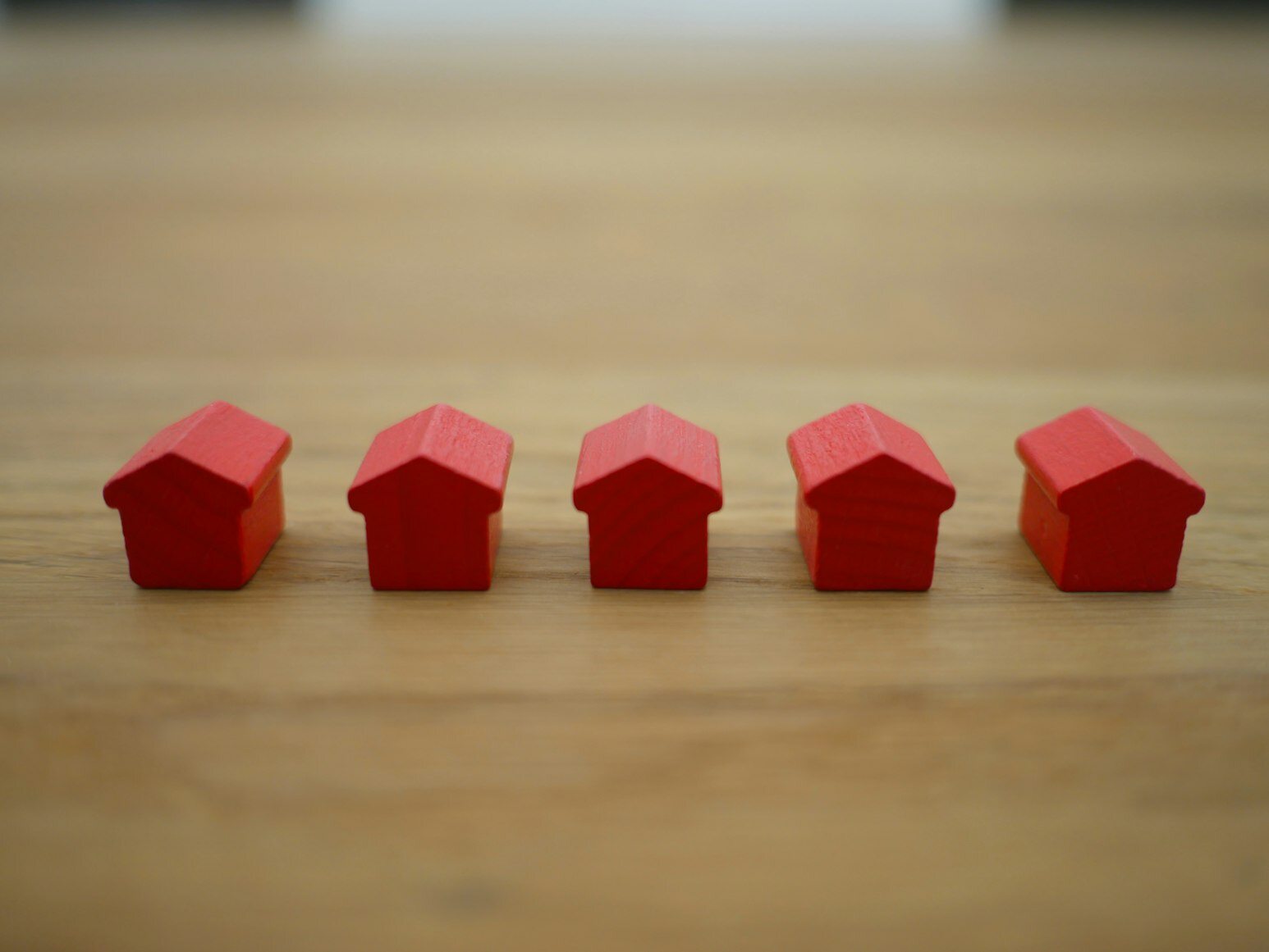 Five red-colored miniature houses on a table.