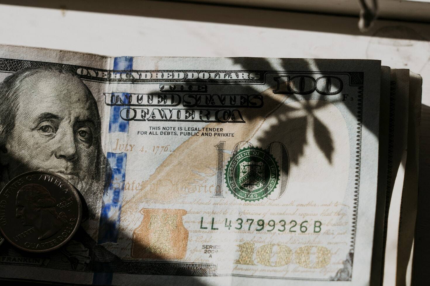 A closeup of 100-dollar bills and a coin