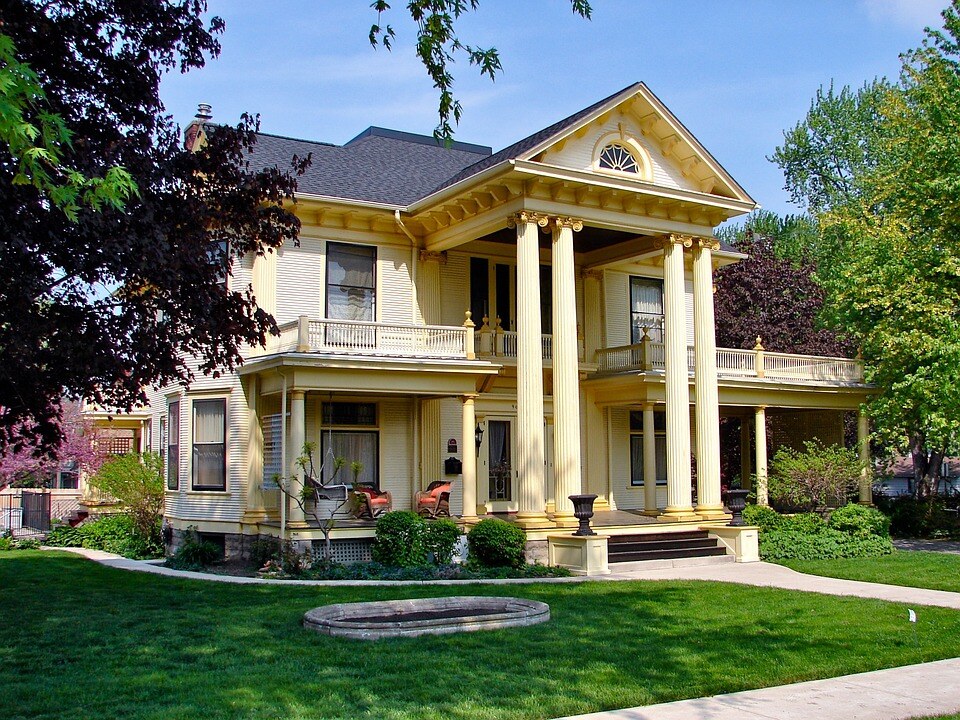 A stately yellow historic home with grand white columns and verdant landscaping in Illinois.